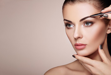 Wall Mural - beautiful brunette woman paints the eyebrows. beautiful woman face. makeup detail. beauty girl with 