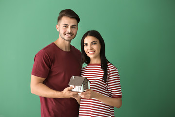 Sticker - Young happy couple with house model on color background