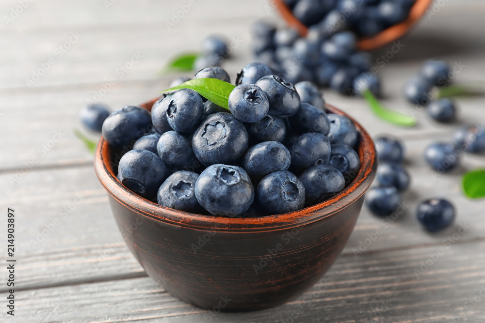 Bowl with ripe blueberries on wooden table