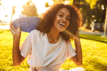 Poster - Delighted young african girl holding skateboard