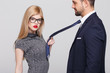 Sensual blonde manipulator woman with red lips pulling man by tie