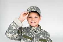 Portrait Of Smiling Kid In Military Uniform Posing On Grey Background