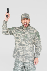 screaming male soldier in military uniform holding gun isolated on grey