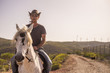 modern man cowboy enjoy a natural and alternative lifestyle riding a white horse. friendship and nature outdoor for beautiful people living a different life in the rural country side