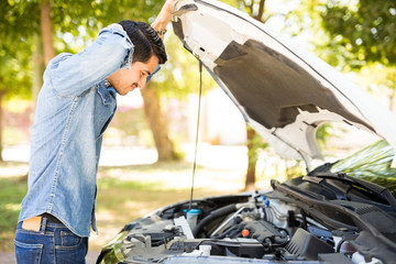 Wall Mural - Man looking under the hood on broken car