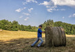 © Iryna - A man in a hat covered with straw looks in the field. Agricultural work. Harvesting of wheat.