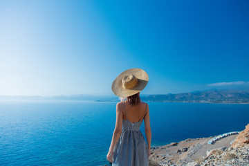 Young redhead girl in hat and dress with sea coastline on Balos, Crete, Greece