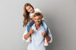 © Drobot Dean - Portrait of adorable family, daughter smiling and sitting on the neck of her father 30s, isolated over gray background