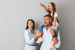 © Drobot Dean - Image of european happy family woman and man smiling and looking aside while daughter sitting on the neck of her father, isolated over gray background