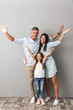© Drobot Dean - Full length photo of beautiful caucasian family woman and man with little girl smiling and hugging together, isolated over gray background