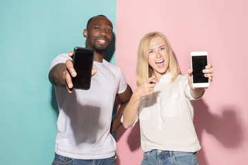 Portrait of a confident casual girl showing blank screen mobile phone and afro man
