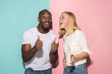 happy afro man and woman. Dynamic image of caucasian female and afro male model on pink studio.