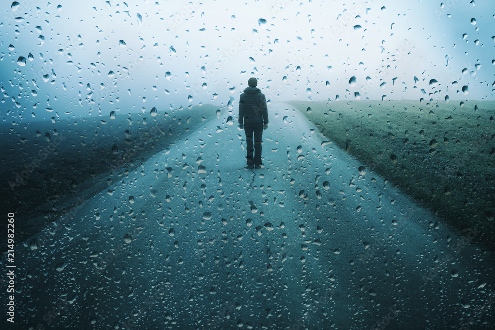 Lonely man stands on misty road with artistic raindrops background. - obrazy, fototapety, plakaty 