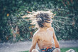 © RooM The Agency - Boy sitting on the grass shaking his wet hair