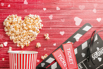 Wall Mural - Flat lay composition with tasty popcorn, tickets and clapboard on red wooden background. Cinema evening