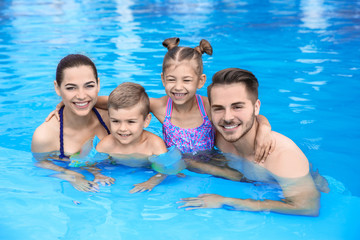 Poster - Young family with little children in swimming pool on sunny day