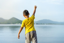 Young Boy Throw Stone Into The Water At Bang Pra Reservoir In Sunset
