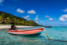 A Red Fishing Boat Is Anchored In The Transparent Waters Of The Lagoon Of Desirade Island, Under A Blue Sky