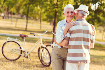 He is my everything. Excited elderly lady looking into the camera with a cheerful mile on her face while embracing her husband outdoors.