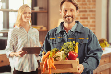 Wall Mural - Free to the door. Happy male person expressing positivity while doing his job, carrying organic food in box