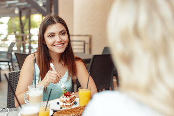 Two beautiful young girls sitting by the table in cafe