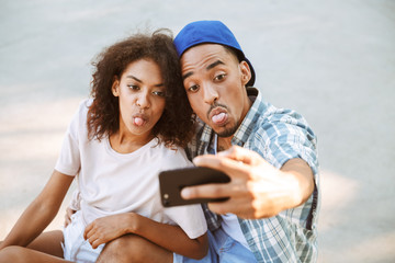 Wall Mural - Portrait of a happy young african couple taking a selfie