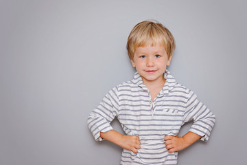 cute three years old boy with blond hair on grey background with copy space
