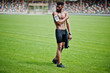 © AS Photo Family - African american male athlete sexy sport bare torso man with running sports arm case for mobile phone, posed at green grass of football stadium.