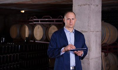 Wall Mural - Wine producer with clipboard in wine cellar