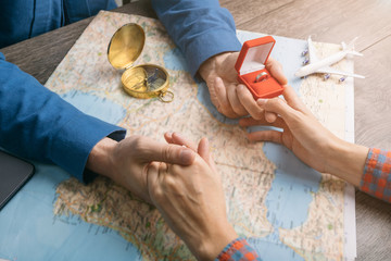 Be my wife. Let's tarvel together scene. Top view table with map and man is holding ring. Proposing. Will you marry me?