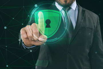 Businessman pushing button on virtual screen against dark background