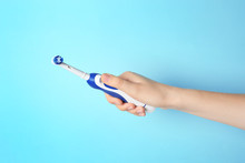 Woman Holding Electric Toothbrush Against Color Background