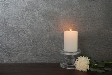 Decorative candle with flower on table against color background