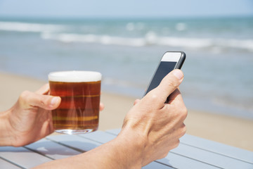 Wall Mural - drinking a beer and using a phone on the beach