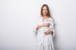 © Siarhei Kulikou - Beautiful red-haired girl in a white bathrobe on a light background