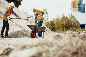 Wall Mural - Low angle on workers in reflective vests with shovels and barrow