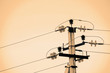 Power lines on background of sky close-up. Electric hub on pole in monochrome. Electricity equipment with copy space. Wires of high voltage in sky. Electricity industry. Sepia tone.