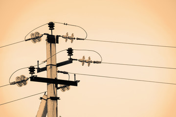 Power lines on background of sky close-up. Electric hub on pole in monochrome. Electricity equipment with copy space. Wires of high voltage in sky. Electricity industry. Sepia tone.