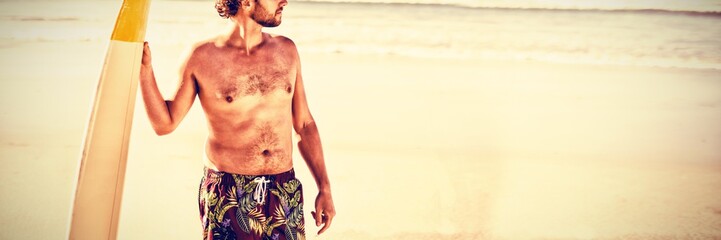 Poster - Shirtless man holding surfboard at beach