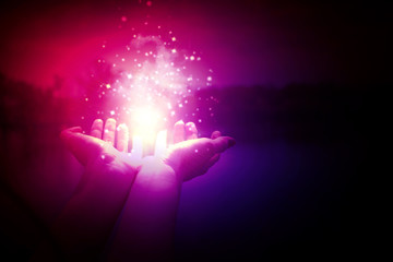 Wall Mural - magic particles on the palms of a woman on a dark, purple background. magic particles, a flash of li