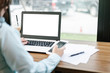 © Thinapob - Close-up of business female working with Mockup image of laptop with blank white screen make a note in coffee shop like the background.