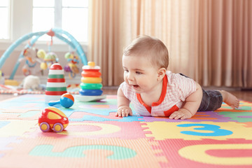 portrait of cute adorable blond caucasian smiling child boy with blue eyes crawling on floor in kids