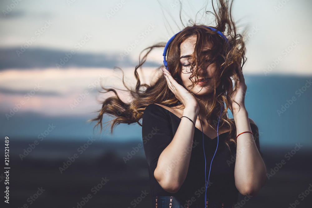portrait of a beautiful girl in headphones listening to music on nature - obrazy, fototapety, plakaty 