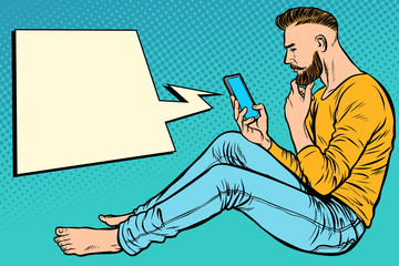 Hipster man sitting on the floor and reading smartphone