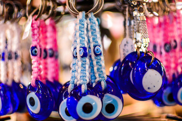 The amulet against the evil-eyed pearl-shaped eye is more exposed in front of a souvenir shop at night sale in a crowded city of tourists in the Greek city of Parga.