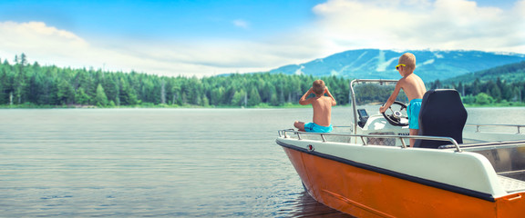 Two brothers swim on a motor boat on the lake.