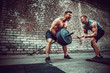 © zamuruev - Two muscular athletes training, one raise the bar when other is motivating. Scream. Working hard. Street gym. Exercise for the muscles of the back