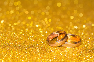 Wall Mural - Wedding rings on a golden radiant background. Glitter shine.