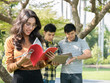 © natsarun - Beautiful asian college student holding books and smiling while his friends standing on background