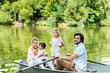 © LIGHTFIELD STUDIOS - Happy young family riding boat on lake at park and looking at camera
